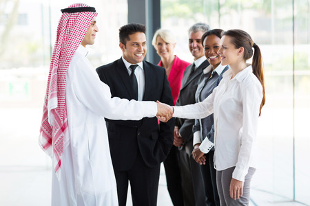 26907396 - group of professional businesspeople welcoming islamic businessman