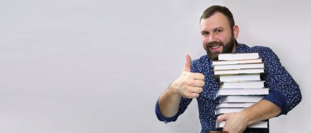 65229231 - student adult beard man with stack of book in a library